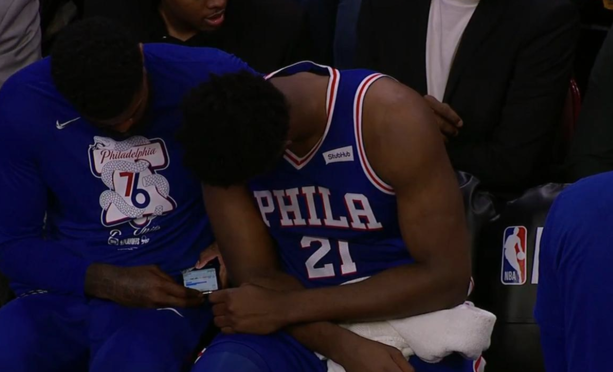 joel embiid checks a phone during game 1