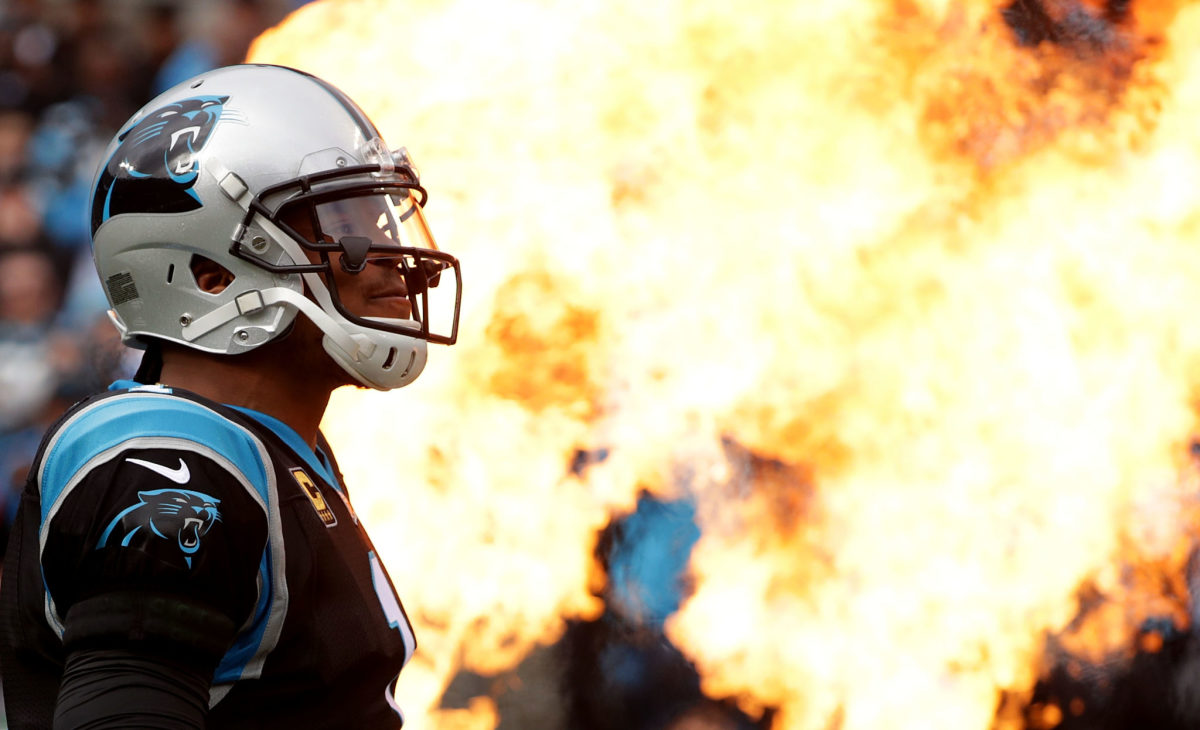 Cam Newton walking onto the field with fire in the background.