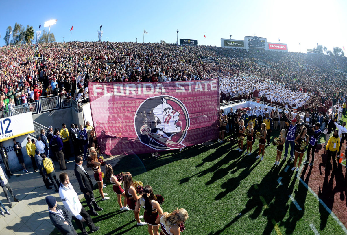 Florida State football players wait behind a banner before running onto the field.