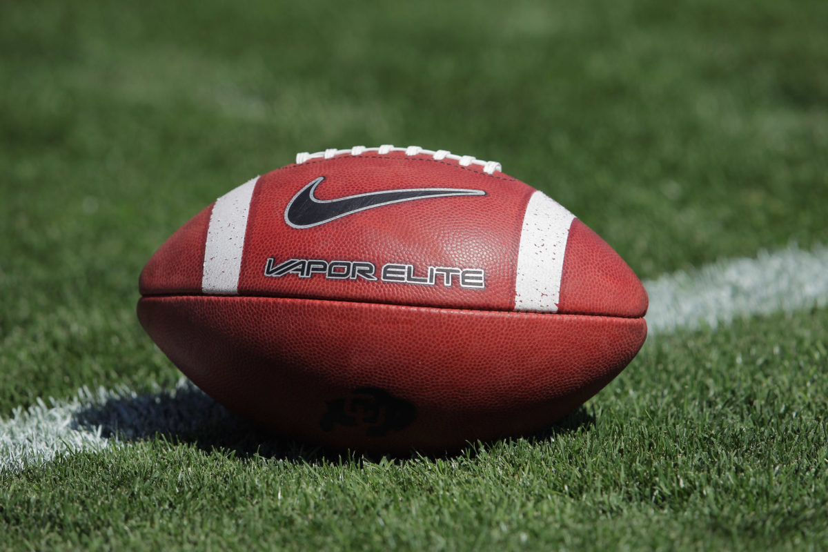 A closeup of a Nike Vapor Elite football sitting on a football field.