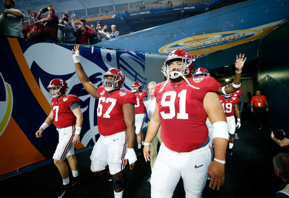 Alabama college football players walk out onto the field before the Orange Bowl against Oklahoma.