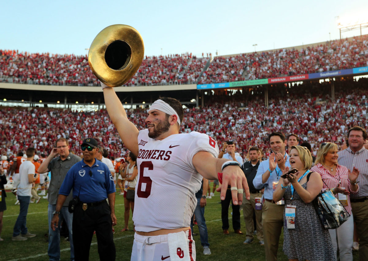 Oklahoma's Baker Mayfield waves Golden Hat trophy after college football win over Texas.