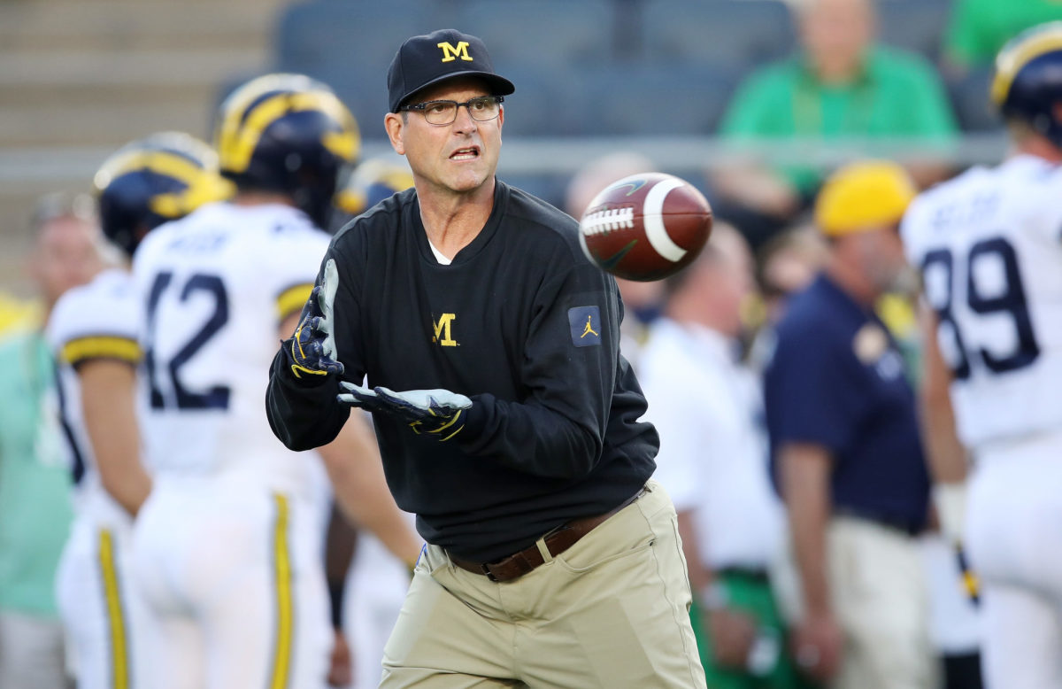 Jim Harbaugh catching a pass during warmups prior to a Michigan football game.