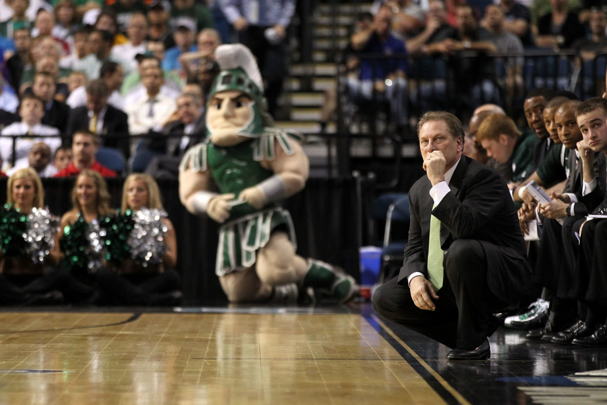 Tom Izzo crouching on the Michigan State Spartans sideline.