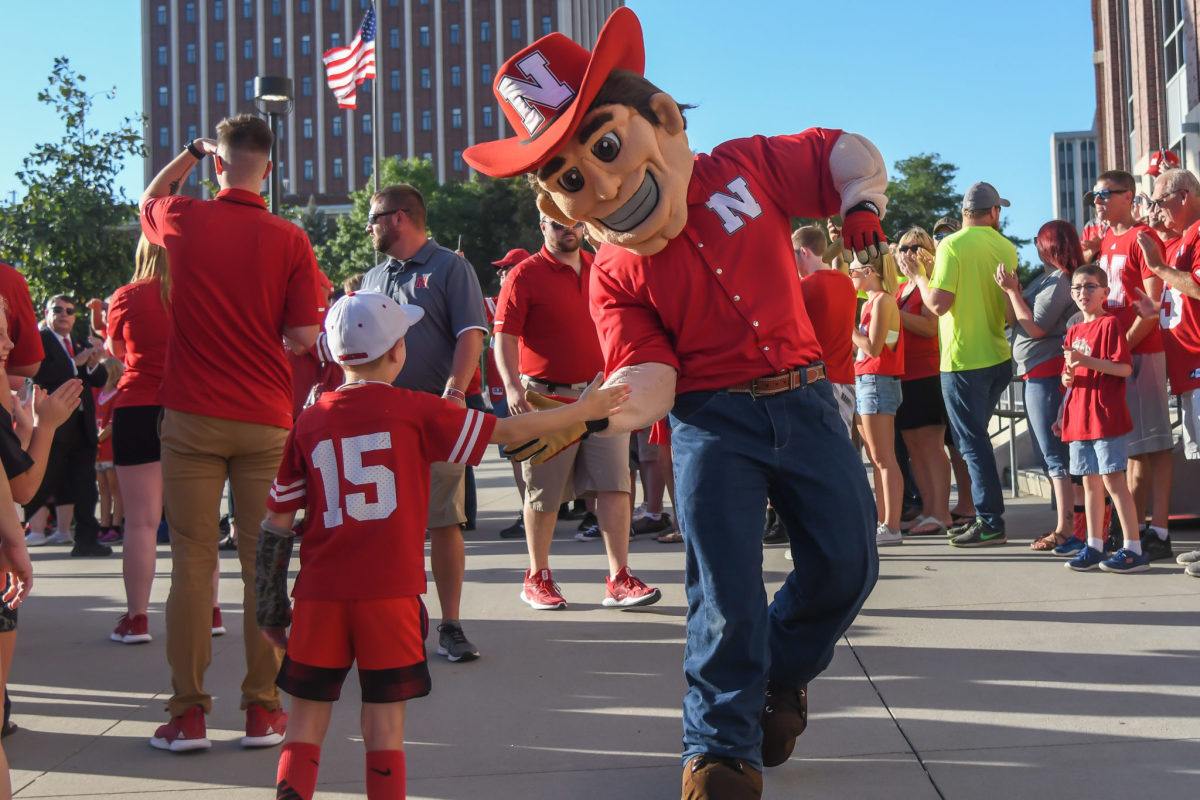 Nebraska's mascot slapping hands with a fan at the game.