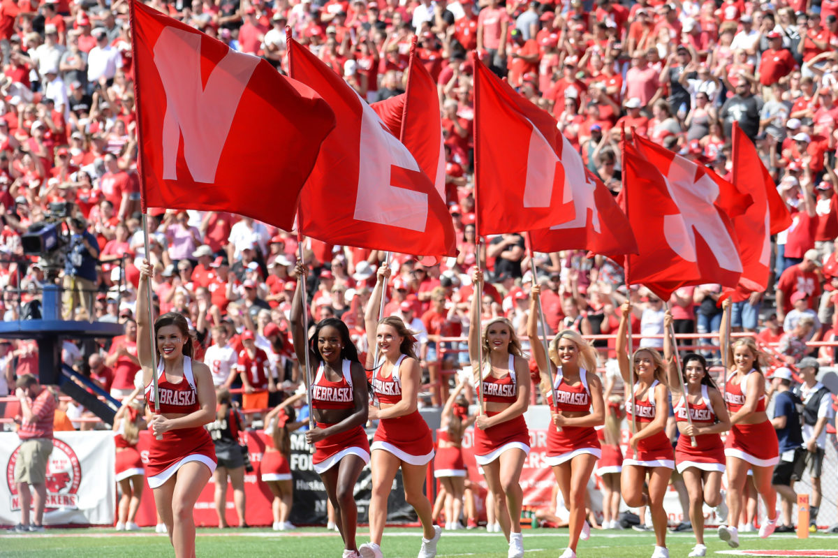 Nebraska cheerleaders run flags onto the field.
