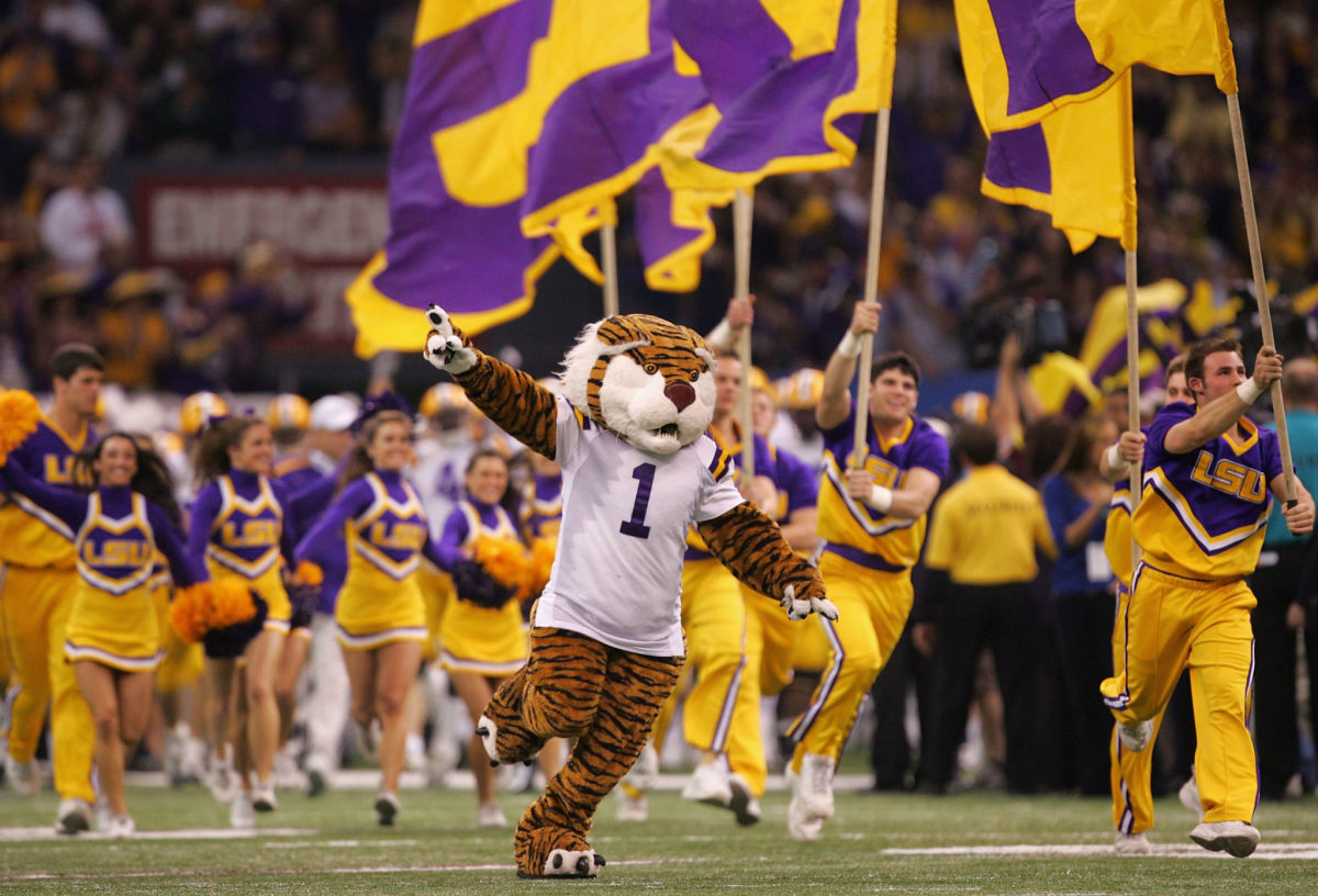 The LSU Tiger leads cheerleaders and players onto the field.