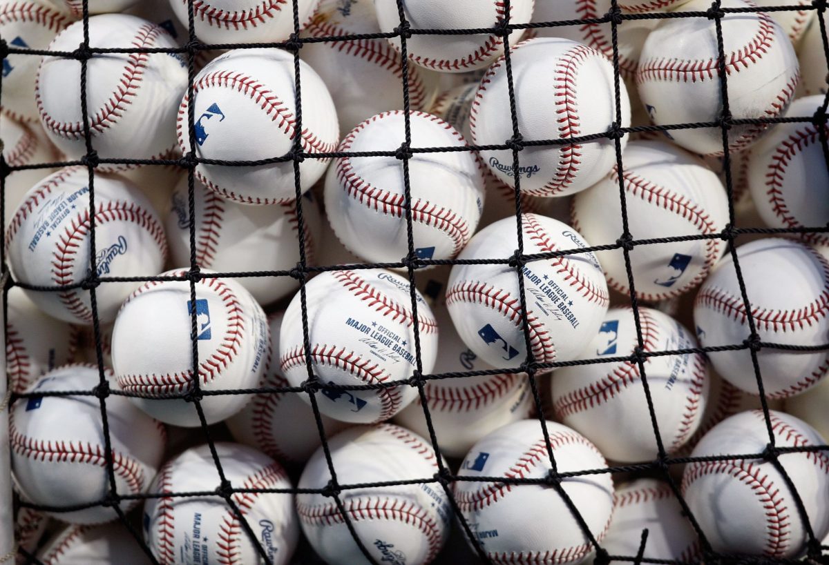 A bunch of baseballs with the MLB logo on it in a net.