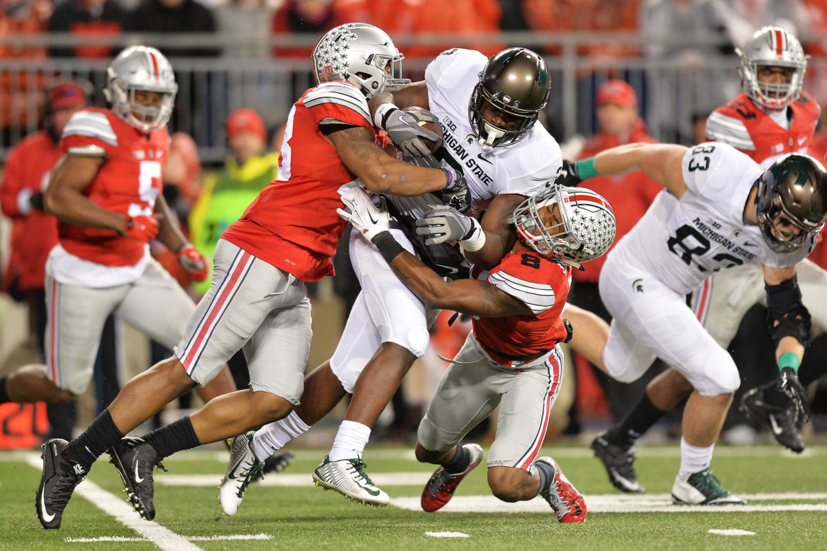 Ohio State players tackling Michigan State's RB.