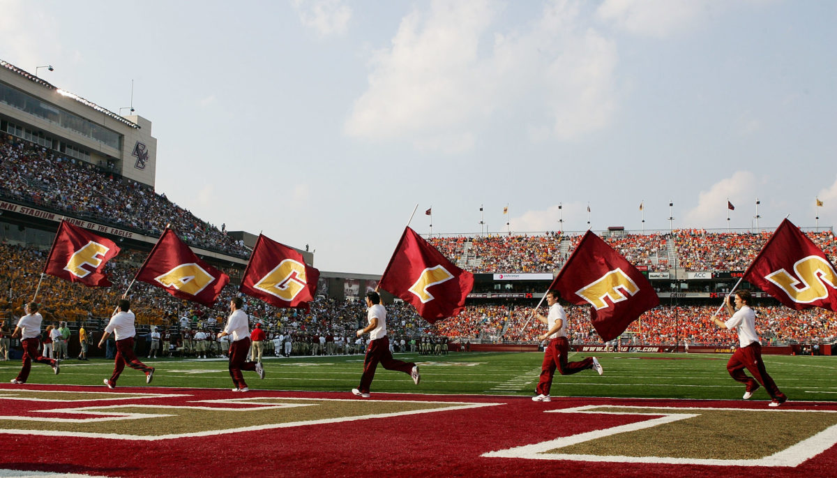 Boston College cheerleaders running with flags during a game.