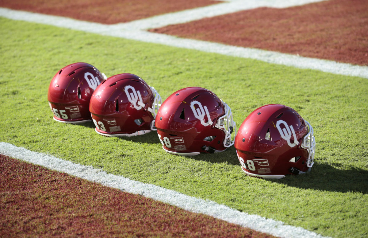 Four Oklahoma Sooners  helmets lined up on the field before a football game.