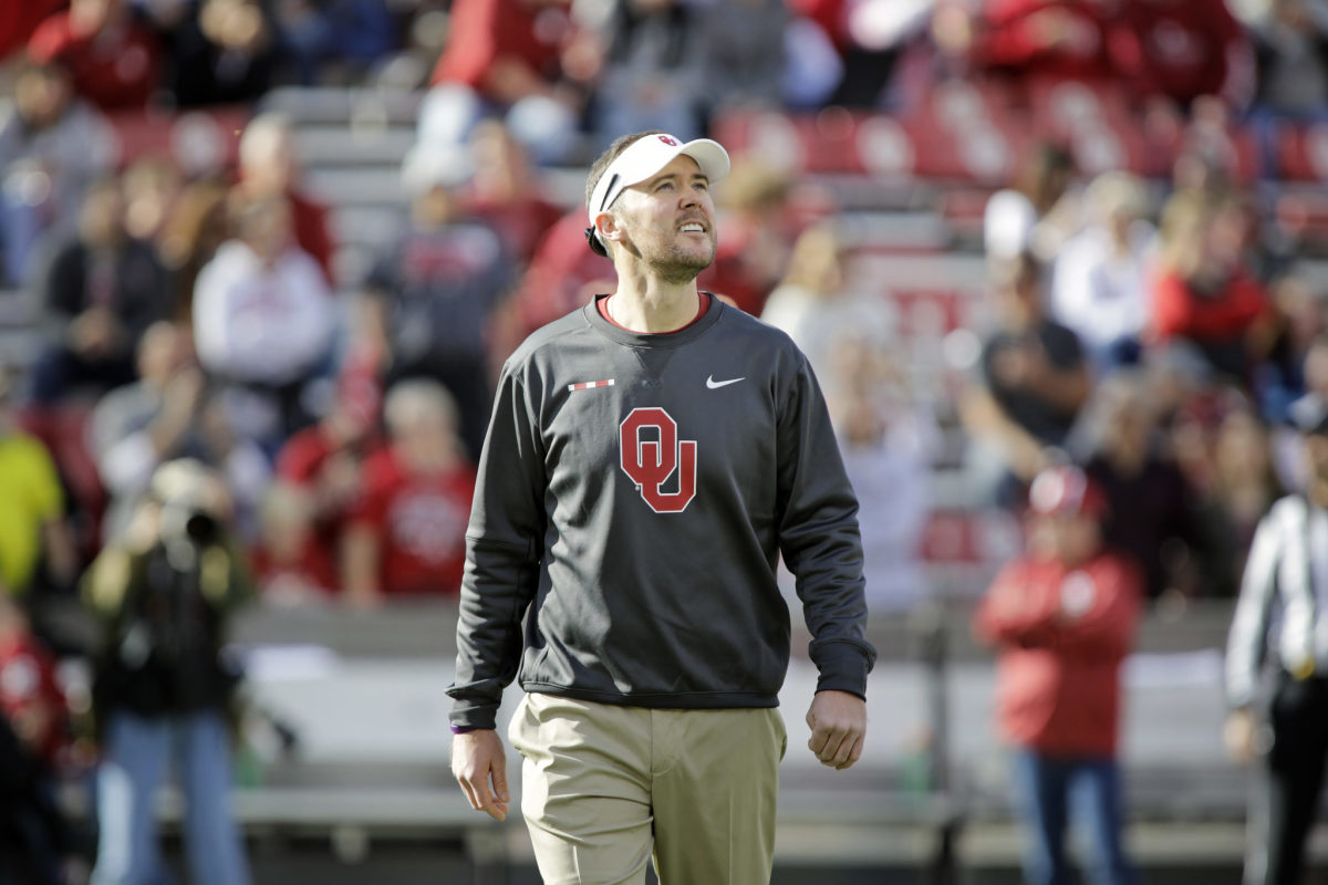 A closeup of Lincoln Riley wearing a grey Oklahoma sweater before a game.
