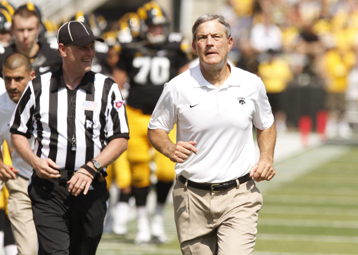 Kirk Ferentz running off the field during halftime of an Iowa Hawkeyes football game.