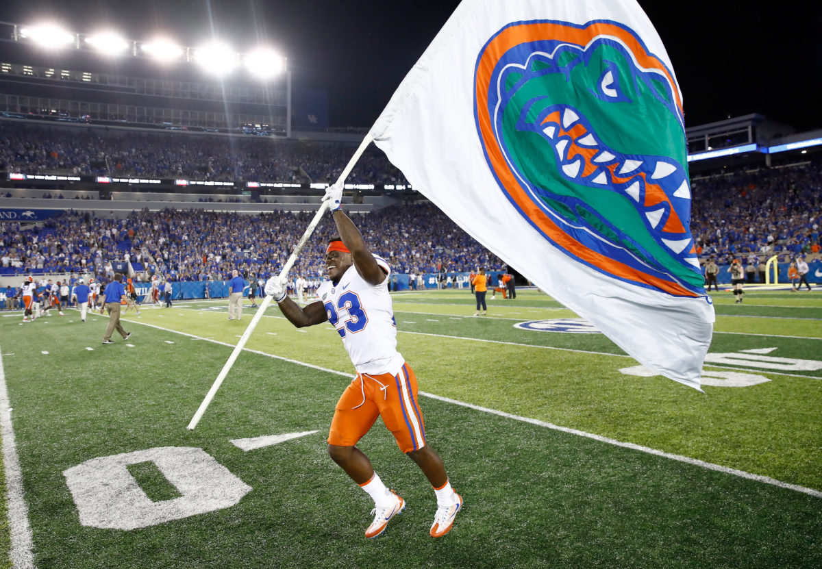 Florida Gators player C. J. Gardner-Johnson running on the field with a Florida Gators flag.