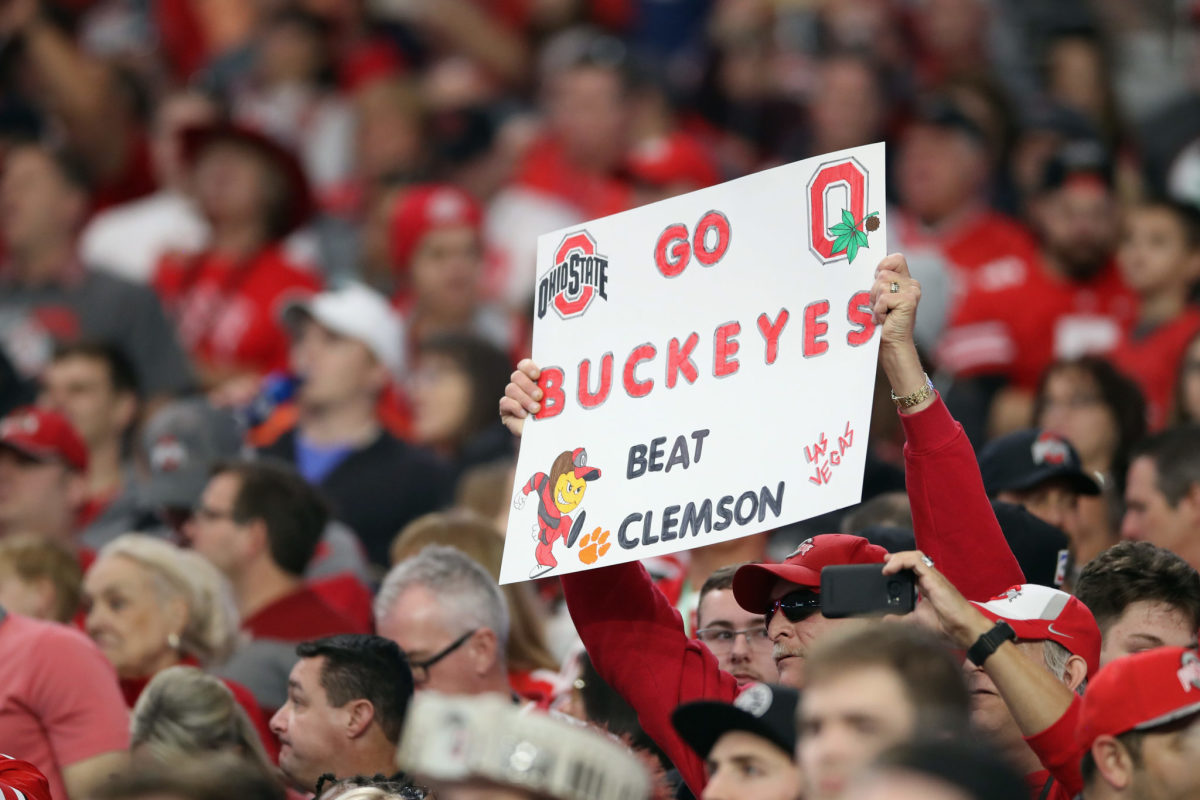 An Ohio State fan holding a "Beat Clemson" sign.