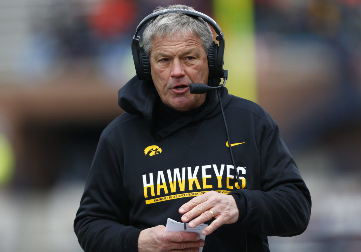A closeup of Iowa Hawkeyes coach Kirk Ferentz wearing a Hawkeyes hoodie and a headset.