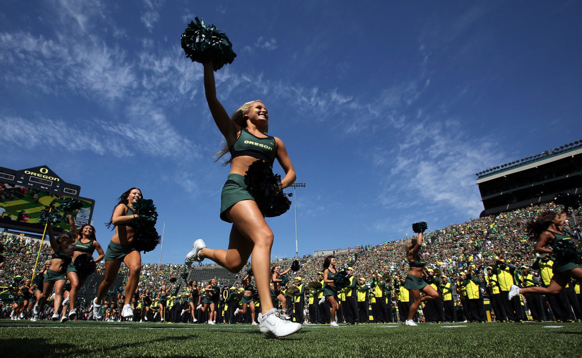 An Oregon cheerleader running onto the field.