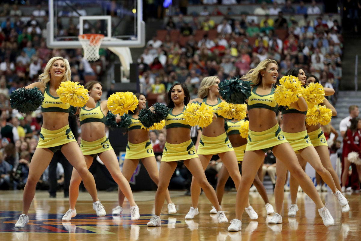 Oregon's cheerleaders dance on the court during a basketball game.