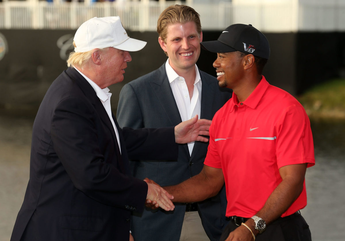 Donald Trump shakes hands with Tiger Woods with his son Eric Trump in the background..