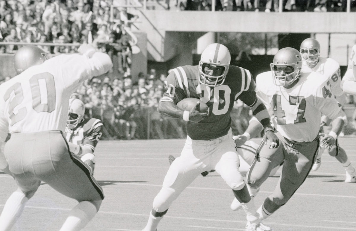 A black-and-white photo of Johnny Rodgers running with the ball for Nebraska.