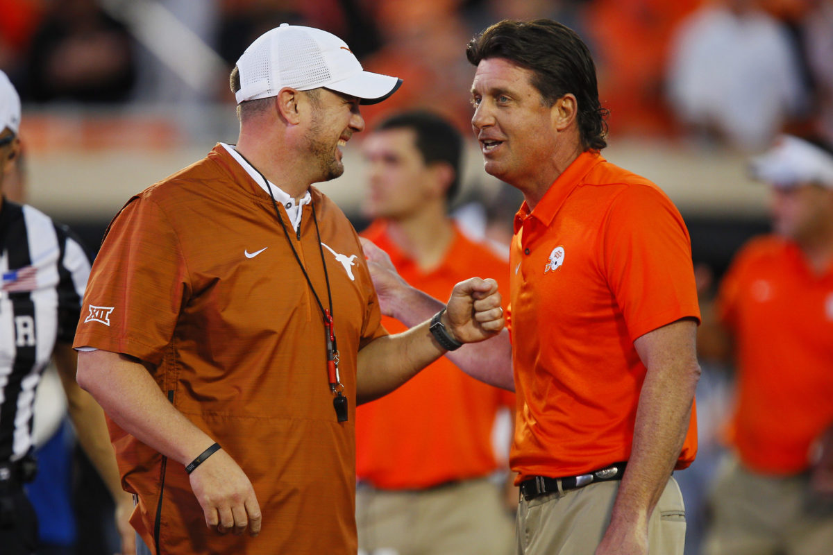 tom herman and mike gundy joke around during a game
