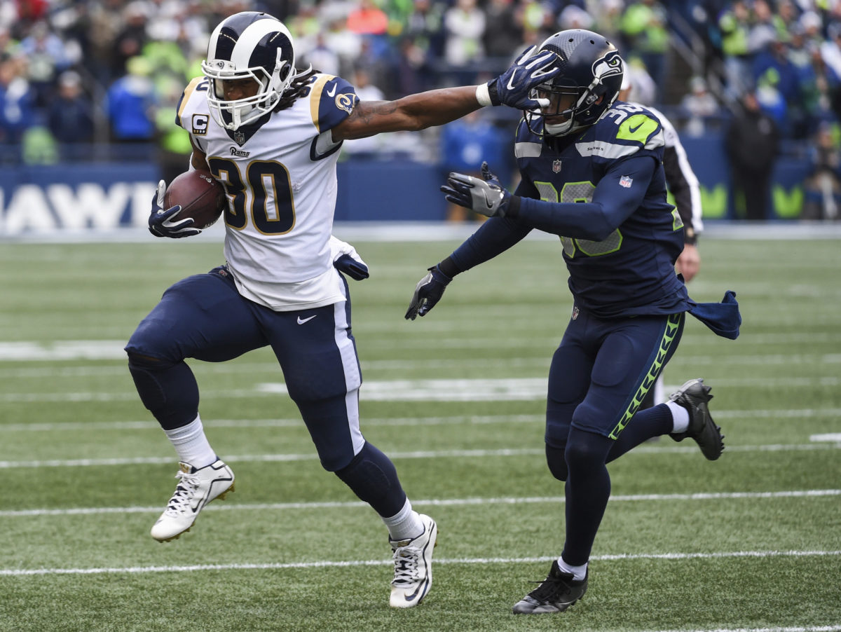 Todd Gurley giving a stiff arm to a Seahawks player.