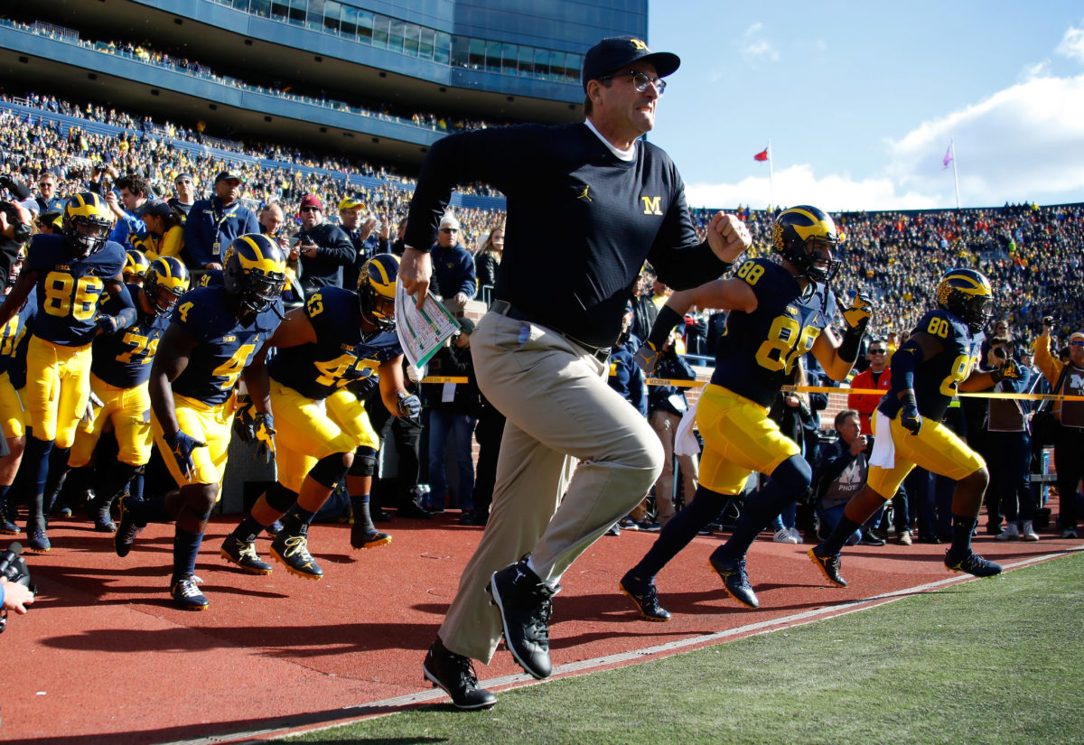 Michigan football head coach Jim Harbaugh leads the team onto the field.