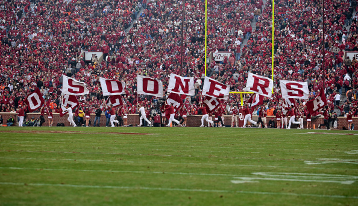 A picture of Oklahoma's cheerleaders running with flags that spell out "Sooners".