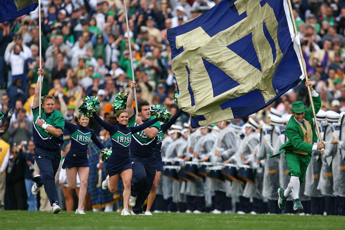 Notre Dame cheer team with the school flag at a football game.