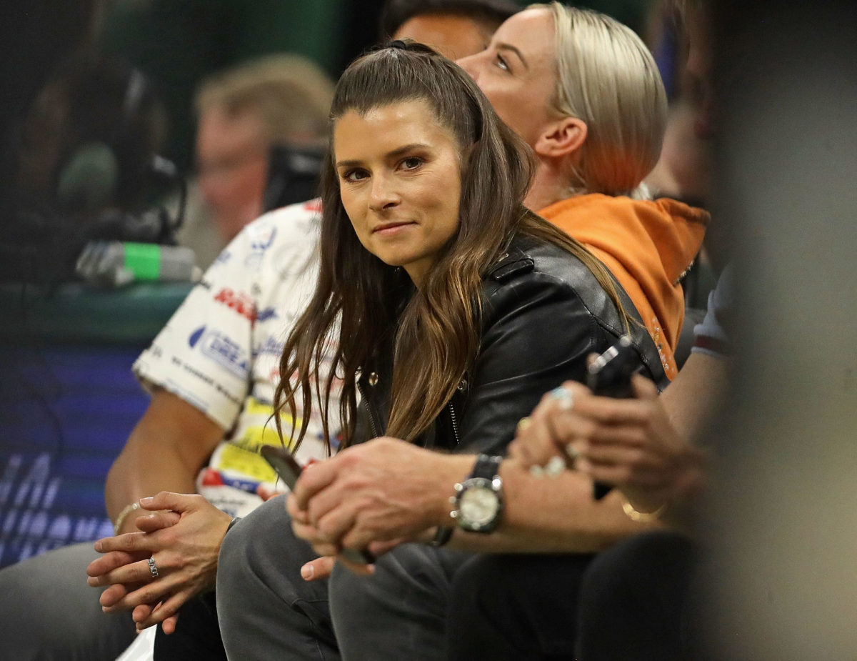 Danica Patrick sits on the sideline during a Milwaukee Bucks game.