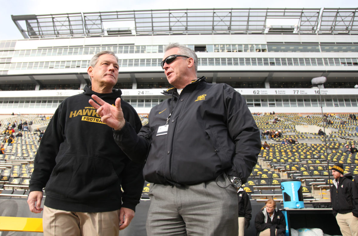 Gary Barta and Kirk Ferentz talk on the Iowa football field.