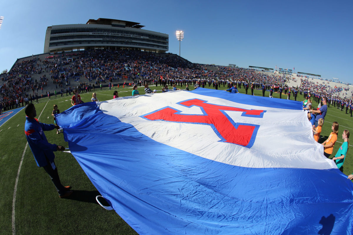 Fans hold a University of Kansas school flag during the playing of the nation anthem prior to a game.