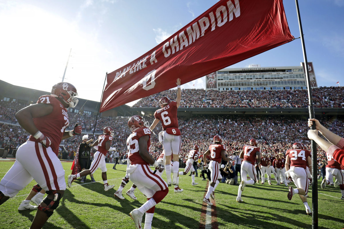 Oklahoma Sooners players running onto the field.