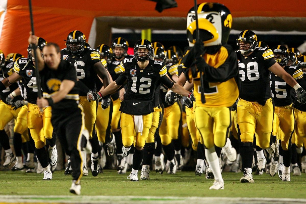 Iowa football players run onto the field.
