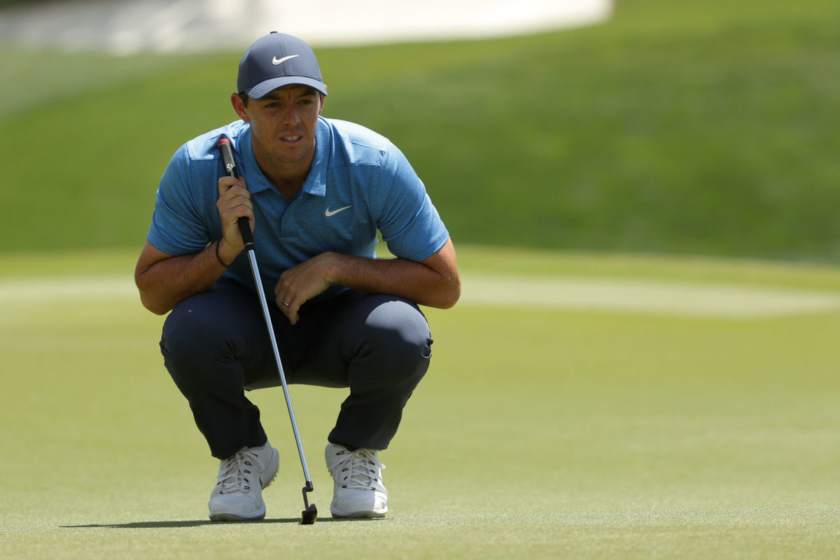Rory McIlroy crouching on a golf course.