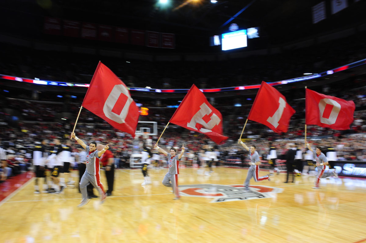 Ohio State cheerleaders running with flags that spell out Ohio.