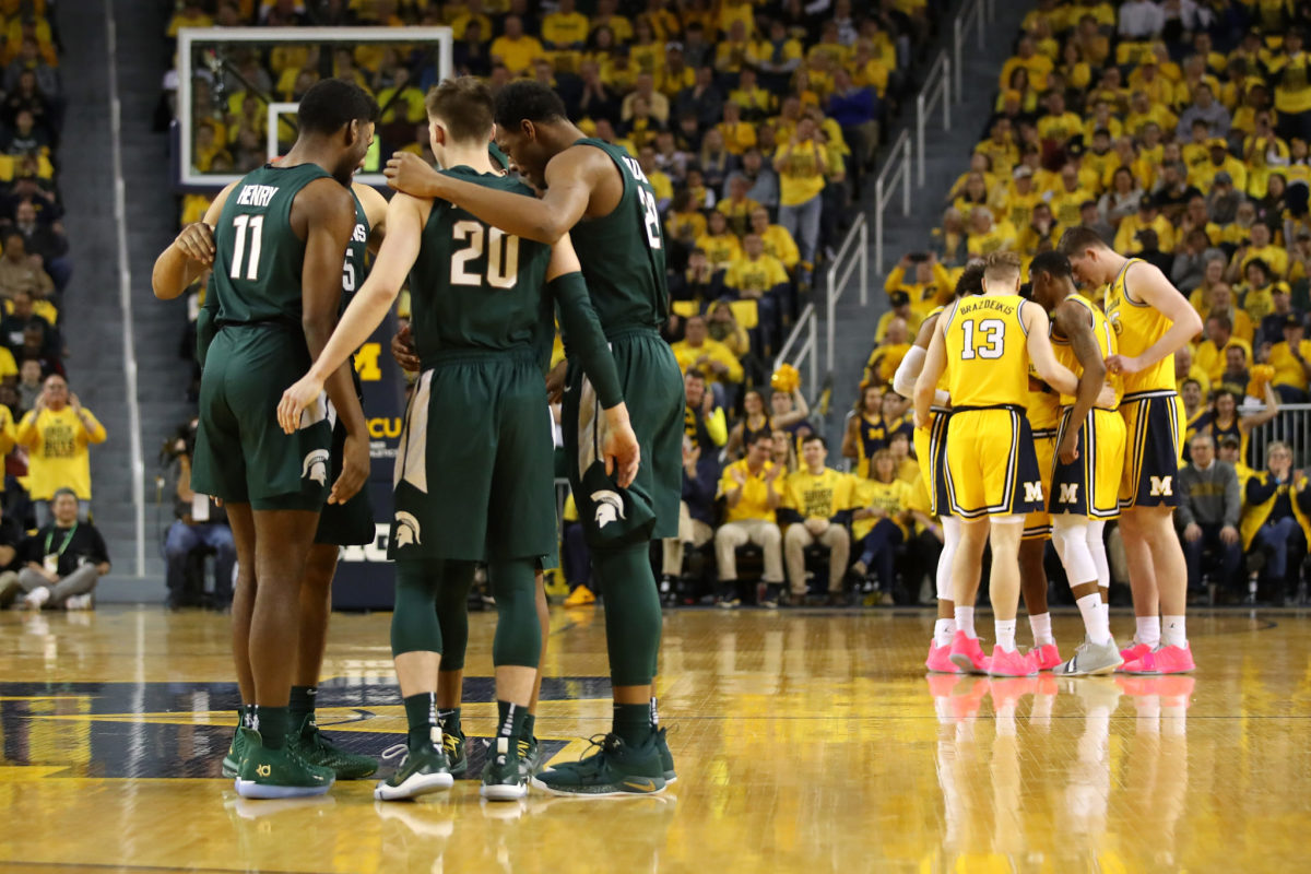 Michigan and Michigan State players huddling during a game.
