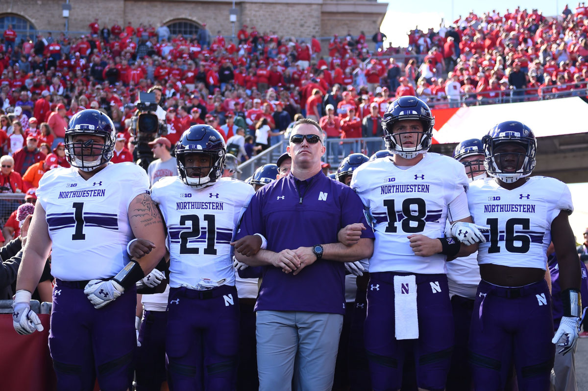 Northwestern coach Pat Fitzgerald leading his team onto the field.