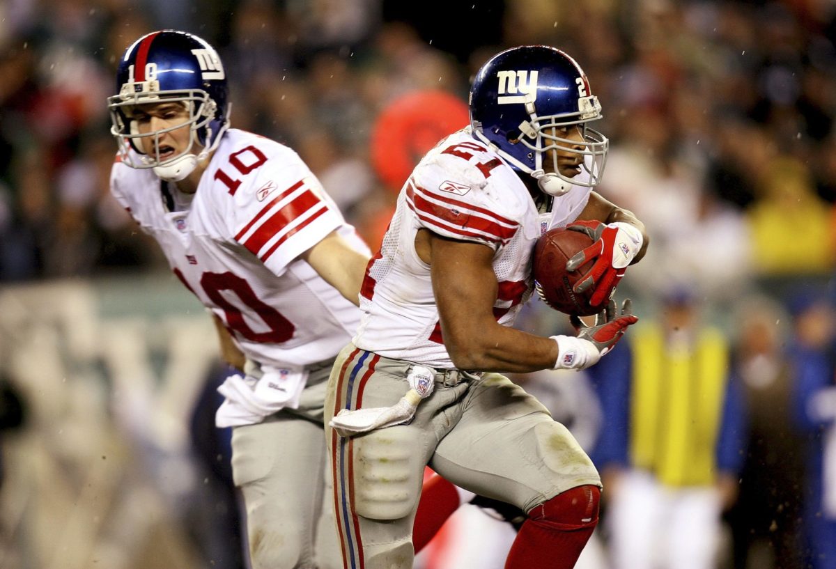 New York Giants star Eli Manning hands off to Tiki Barber.