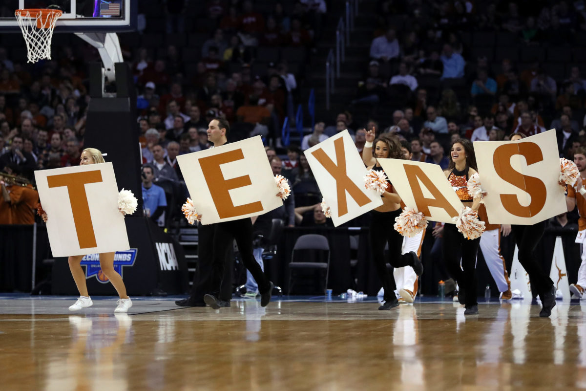 Cheerleaders holding Texas signs during a basketball game.