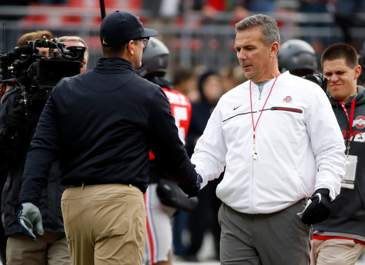 Head coach Urban Meyer of the Ohio State Buckeyes and Head coach Jim Harbaugh of the Michigan Wolverines shake hands on the field prior to their game.