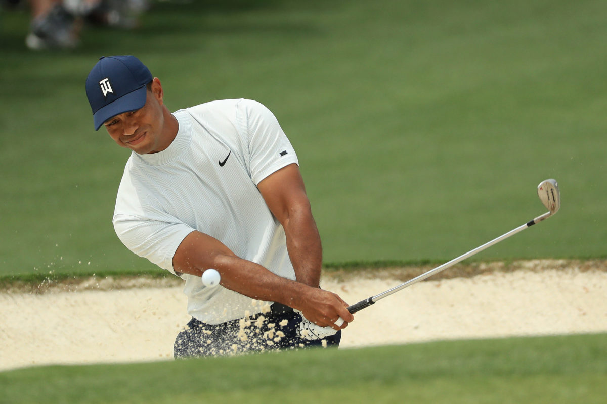 Tiger Woods hitting a ball out of the bunker.