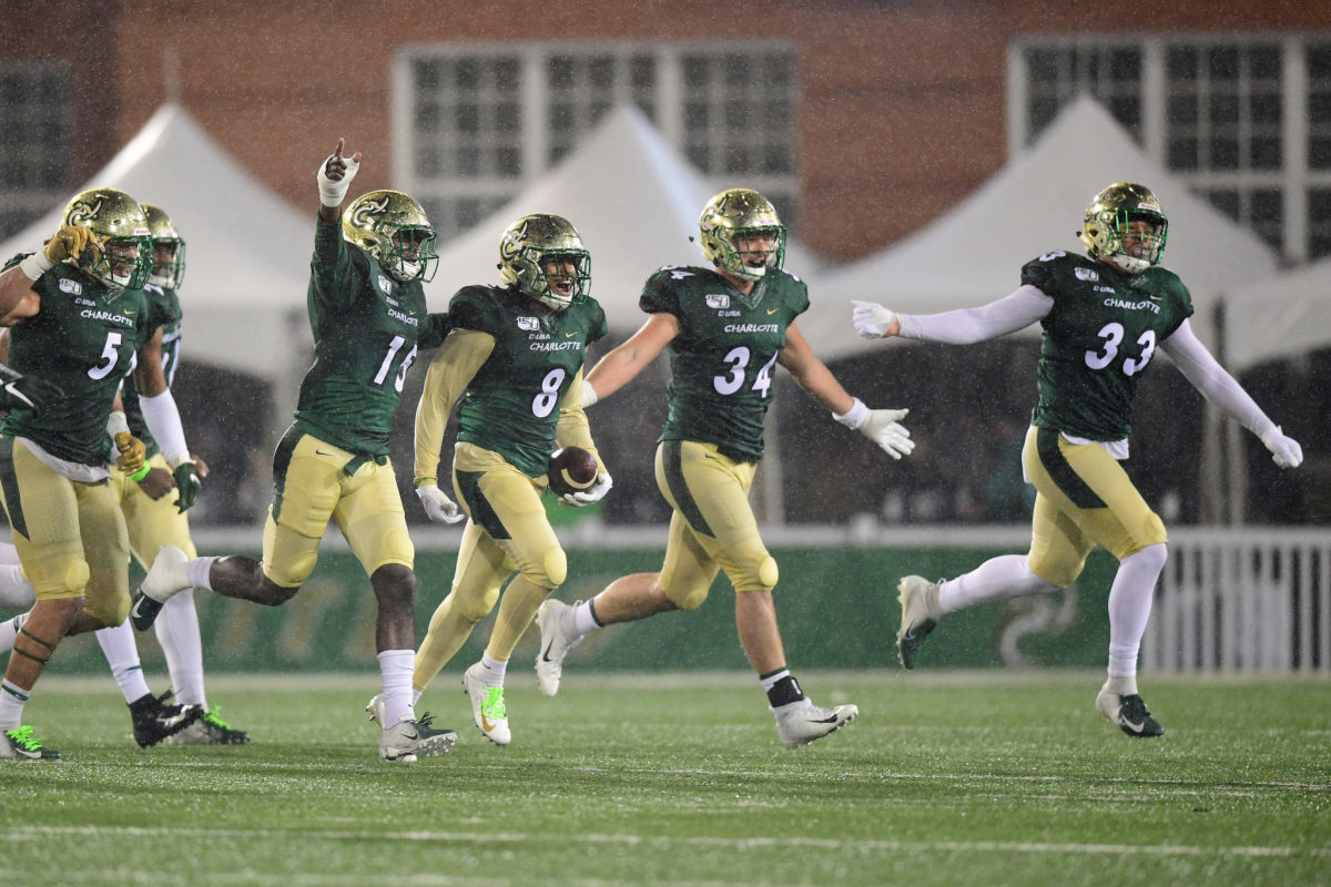 Charlotte football players running off the field celebrating.