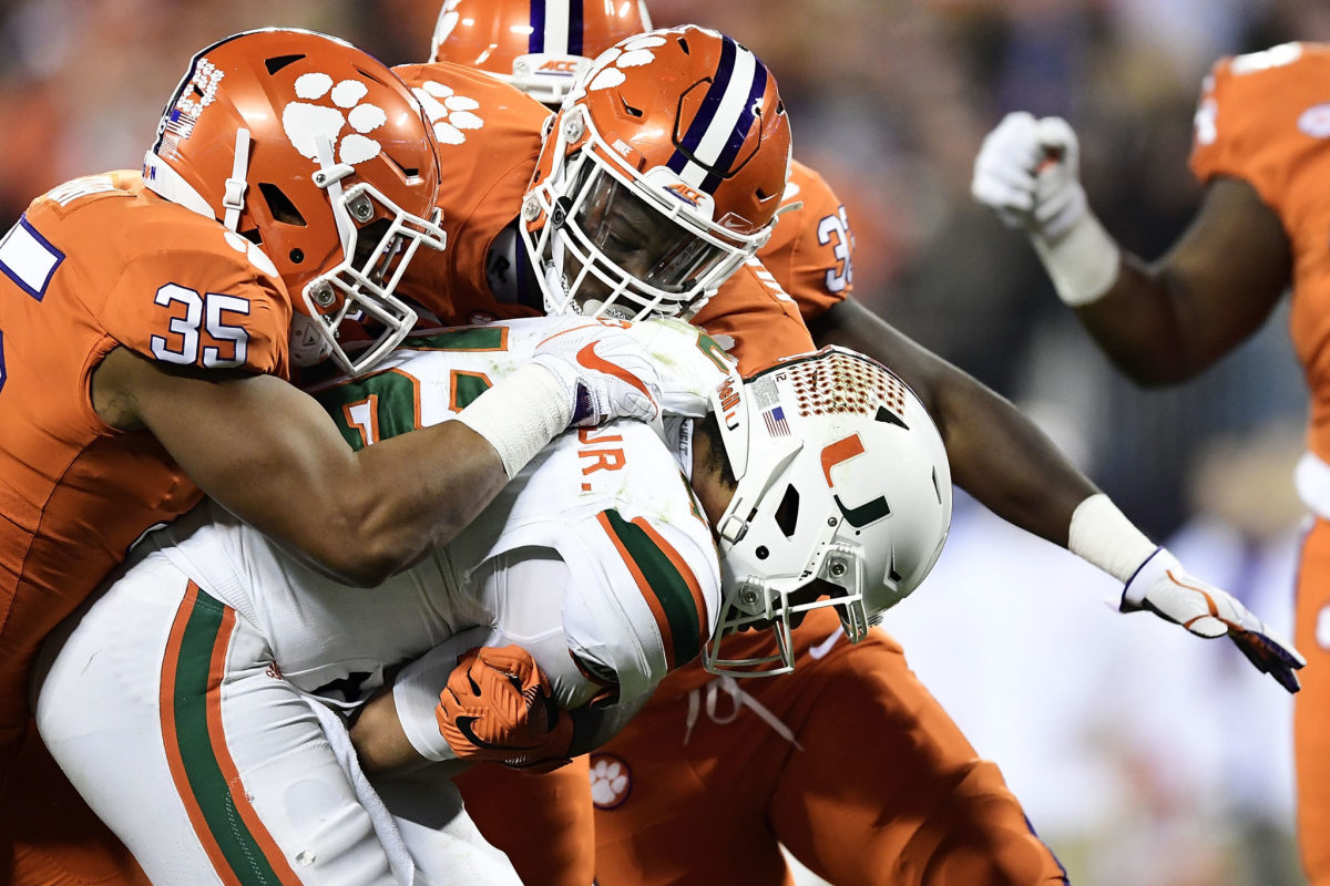 Clemson football players tackle a Miami Hurricane during the ACC Championship college football game.