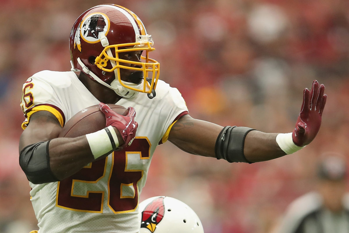 A closup of Adrian Peterson giving a stiff arm during a Redskins game.