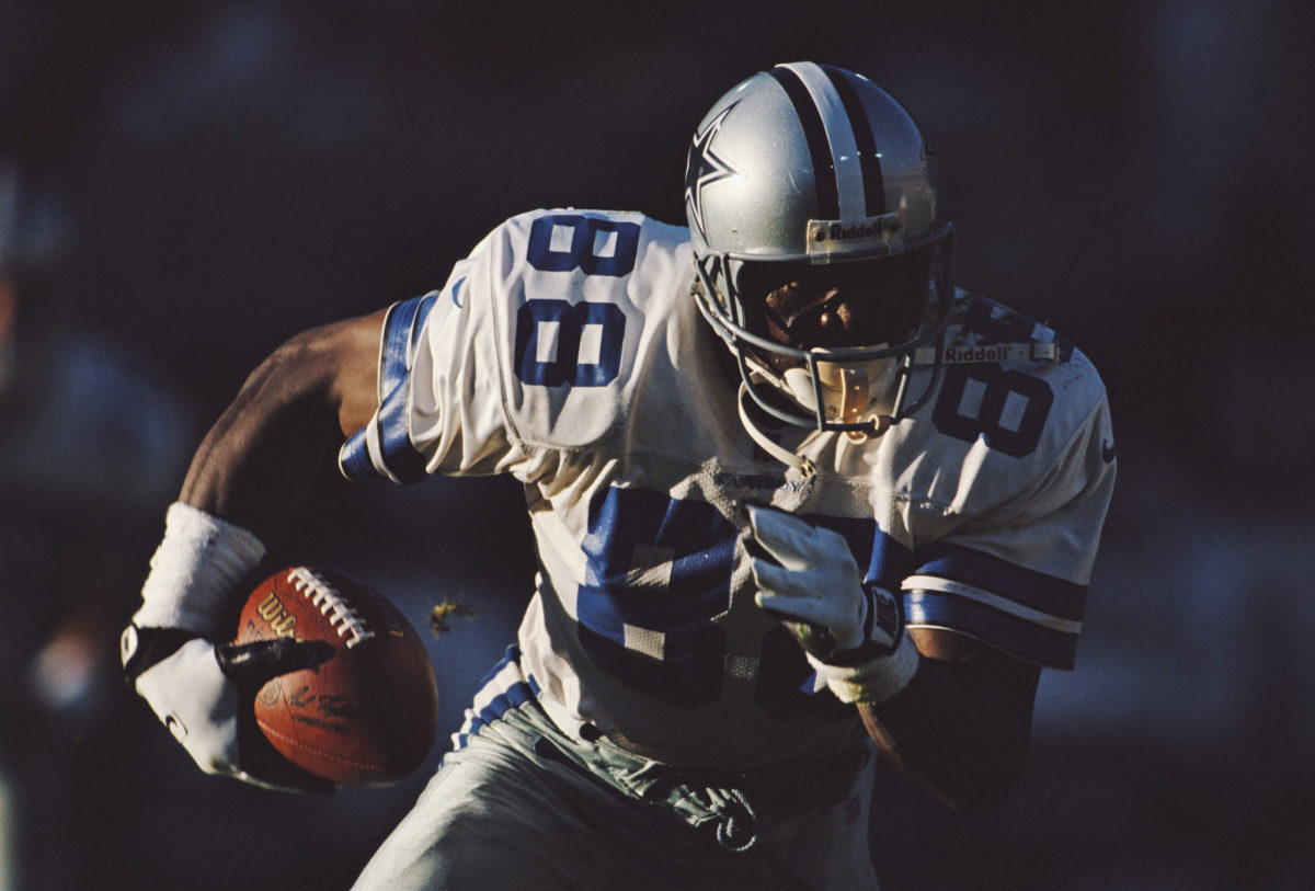 A closeup of Michael Irvin running with the football.