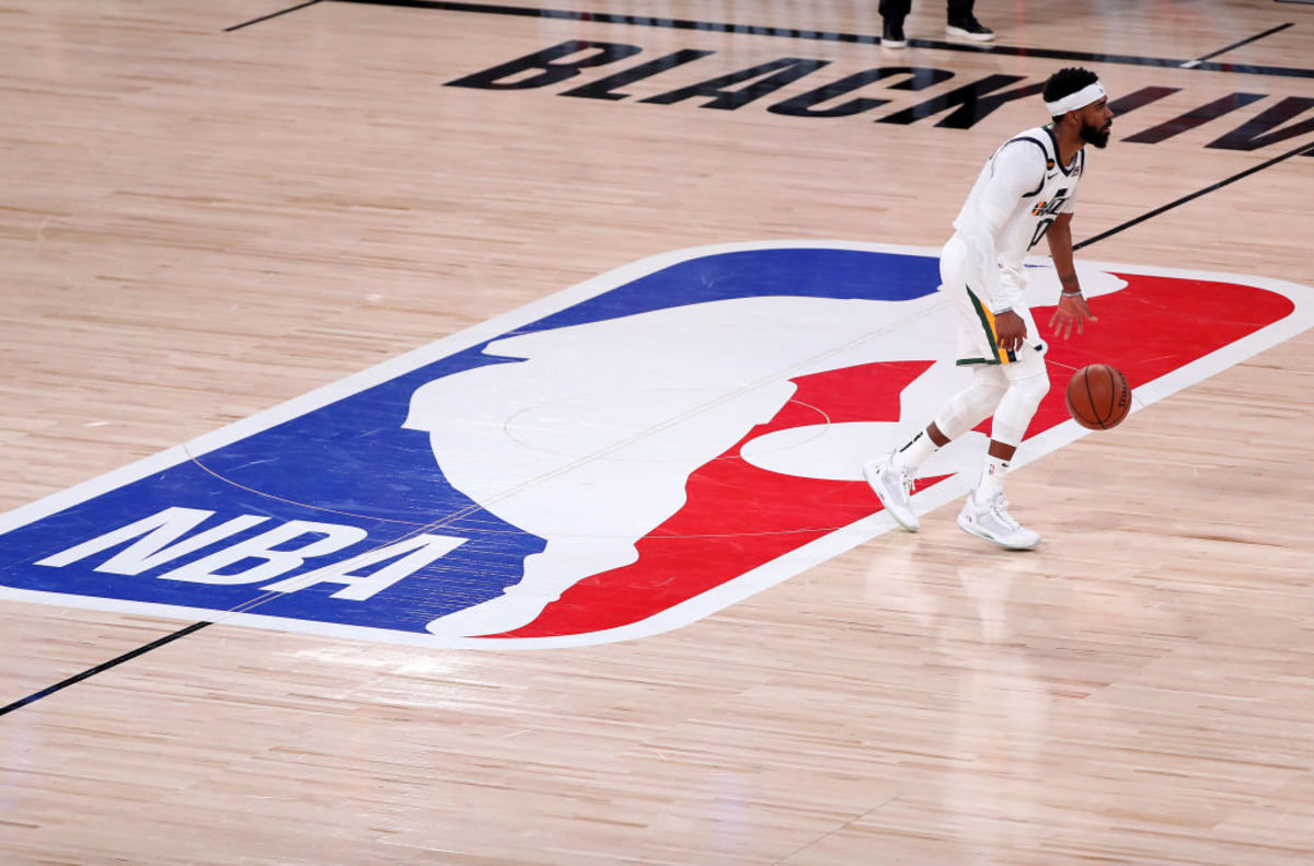 Utah Jazz PG Mike Conley dribbles the ball on the NBA logo at halfcourt.