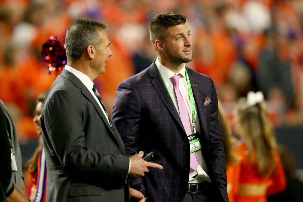 Urban Meyer talks with Tim Tebow during the 2016 College Football Playoff National Championship Game