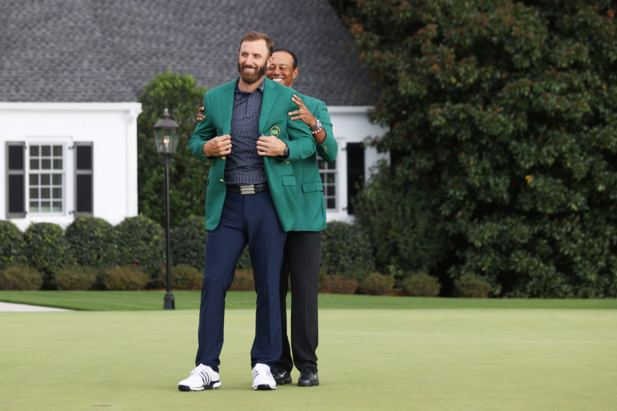 Dustin Johnson of the United States is awarded the Green Jacket by Masters champion Tiger Woods