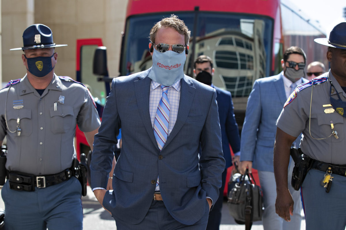Lane Kiffin wearing a suit walking into a stadium before a game.